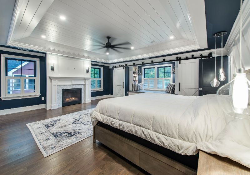 master bedroom with a large platform bed, a cozy fireplace and large windows